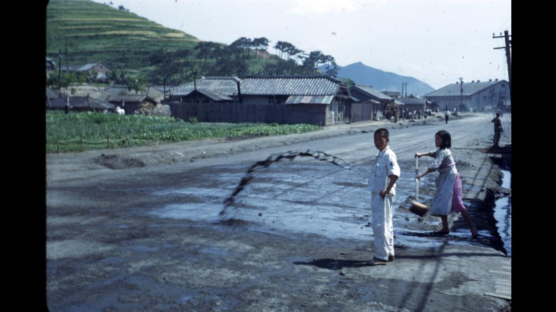 1952년 부산 남구 문현동 도로에 먼지가 나지 않게 도랑물을 뿌리는 청년 썸네일