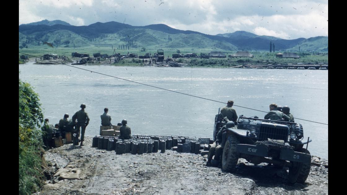 1951년 강을 건너기 위해 잔교가 설치되기를 기다리는 미 해병대 군인들과 군수품 썸네일