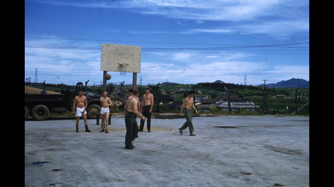 1953년 대구 K-2비행장 소속 미군 병사들의 농구 경기를 하는 모습을 철조망 건너에서 아이들이 바라보고 있는 모습 썸네일