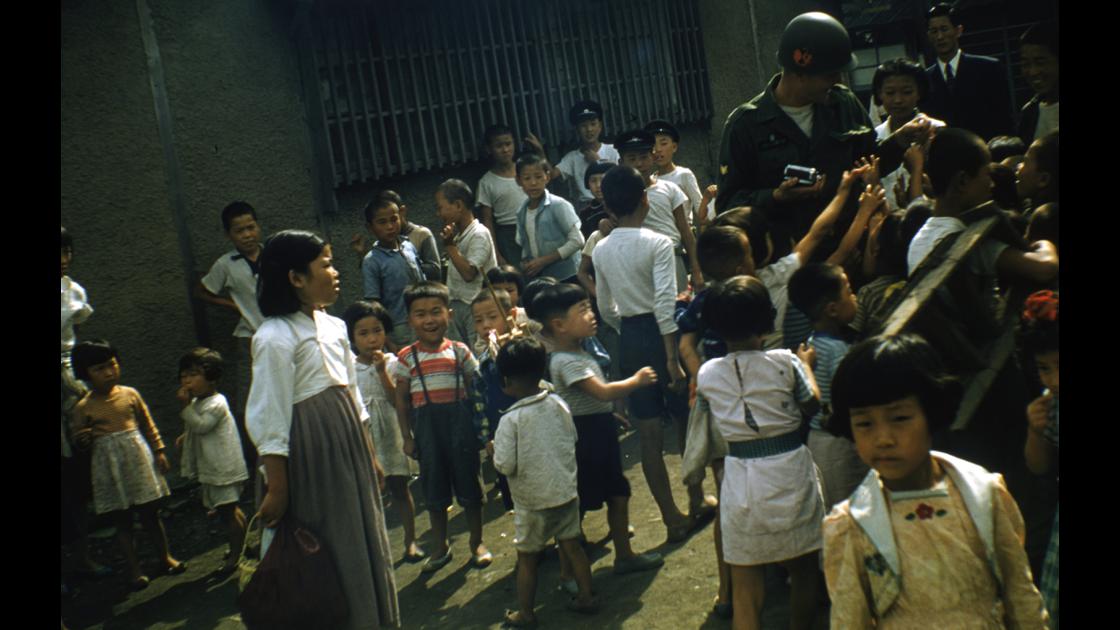 1960년 부산 영도 봉래동 영도초등학교 옆 골목길에서 아이들에게 과자 등을 나누어 주고있는 미군 병사 썸네일